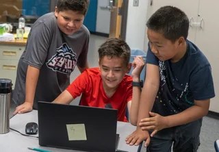 Three children staring at computer
